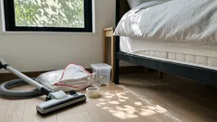 ベッド下を掃除機で掃除し、トコジラミ対策の道具を並べた寝室